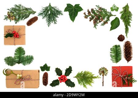 Bordure de Noël avec boîtes-cadeaux écologiques et verdure hivernale avec houx, fermes, lierre et cônes de pin sur fond blanc. Concept de recyclage écologique de Noël. Banque D'Images