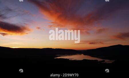 Superbe vue panoramique sur le réservoir Bin el Ouidane Dam avec reflet de l'eau et magnifique ciel coloré spectaculaire avec des nuages orange près de Beni Mellal. Banque D'Images