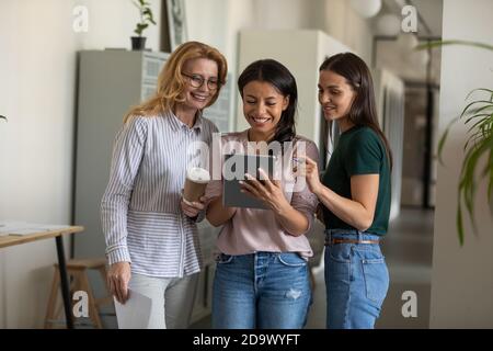 Souriant diverses collègues féminins debout dans le hall de bureau à l'aide d'un bloc-notes Banque D'Images