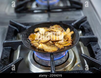 Champignons huîtres frits. Champignons frits aux herbes fraîches dans une casserole en fonte noire. Vue de dessus Banque D'Images