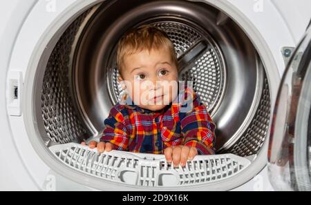 Enfant garçon regarde dans la machine à laver.Bébé garçon