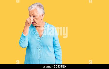 Senior belle femme avec les yeux bleus et les cheveux gris portant robe d'été fatigué frottant nez et les yeux sensation de fatigue et de maux de tête. Stress et frustrat Banque D'Images