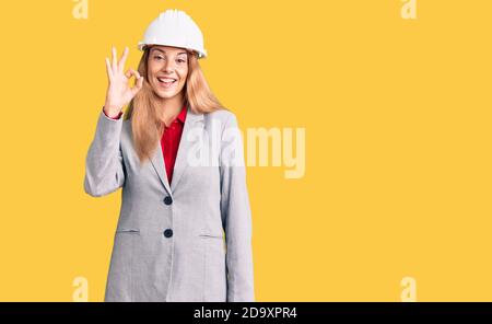 Belle jeune femme portant architecte hardhat sourire positif faisant signe ok avec la main et les doigts. Expression réussie. Banque D'Images