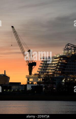 Stern d'un bateau de croisière et d'une silhouette de grue contre le ciel coloré. Banque D'Images