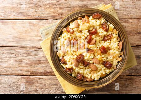 Mesfouf Qsentenena Sweet Couscous avec dattes noix raisins secs dans une assiette sur la table. Vue horizontale du dessus Banque D'Images