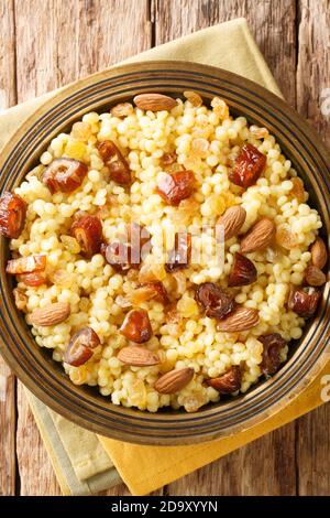 Mesfouf est un couscous chaud avec de l'huile d'olive, du beurre, des noix et des raisins secs dans une assiette sur la table. Vue verticale du dessus Banque D'Images