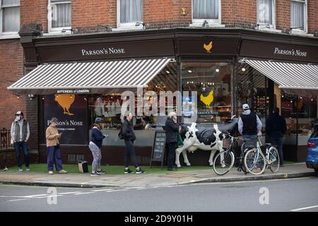 Files d'attente de personnes à l'extérieur de Pasron's Nose butchers attendant d'acheter leur joint de viande pour un dimanche Roast pendant le deuxième confinement du coronavirus, Londres. Banque D'Images