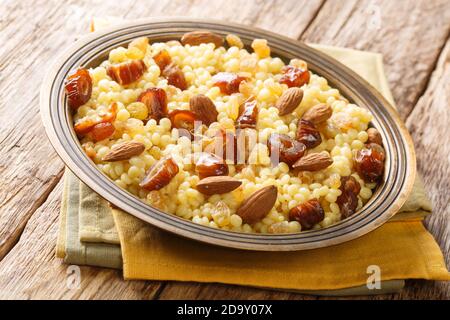 Mesfouf Qsentenena Sweet Couscous avec dattes noix raisins secs gros plan dans une assiette sur la table. Horizontal Banque D'Images