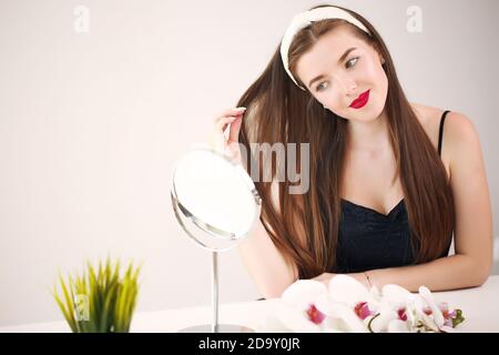 Belle jeune femme appliquant de l'huile de coco sur ses cheveux à la maison Banque D'Images