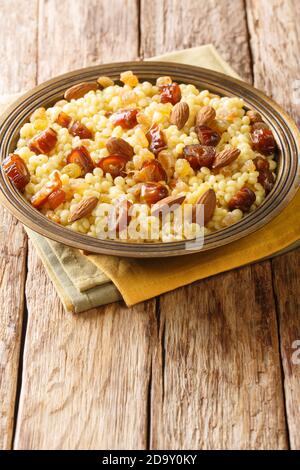 Mesfouf couscous algérien doux aux noix et raisins secs dans une assiette sur la table. Vertical Banque D'Images