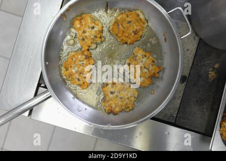 Faire cuire de la viande en pâte sur la cuisinière dans une cantine de restauration rapide. La graisse et les aliments nocifs à haute teneur en calories sont cuits dans une poêle. Banque D'Images