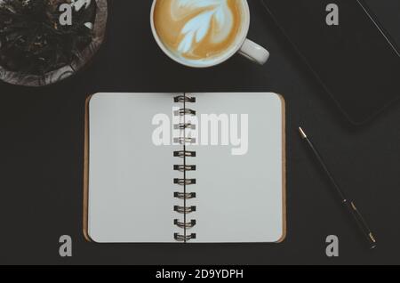 vue de dessus livre et stylo, tasse à café, smartphone sur fond noir. Banque D'Images