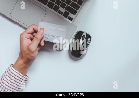 Homme avec vue sur le dessus tenant une carte de crédit et à la réception. Ordinateur portable Bloc-notes et stylo.Vente en ligne, payer par carte de crédit Banque D'Images