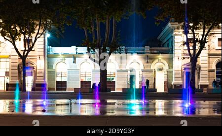 Forme d'eau colorée sur la fontaine avec fond urbain, grand multicolore décoratif dansant eau jet LED lumière fontaine spectacle la nuit. Coloré. Banque D'Images