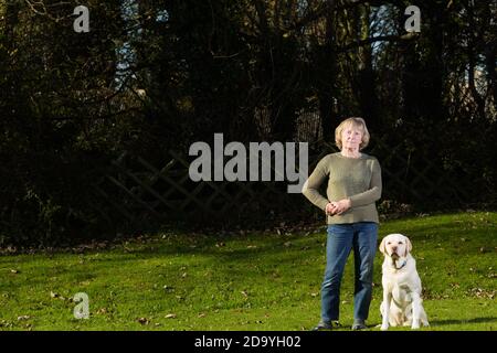 Femme âgée debout sur la pelouse avec son Golden Labrador à ses côtés. Banque D'Images