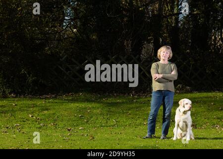 Femme âgée debout sur la pelouse avec son Golden Labrador à ses côtés. Banque D'Images