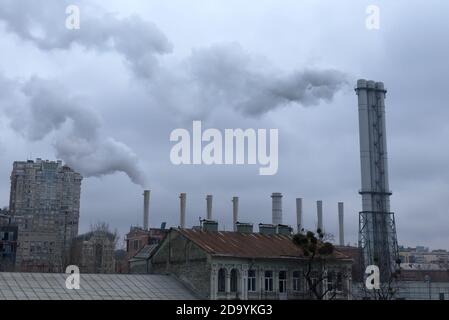 La fumée provient des cheminées industrielles au-dessus des toits. Le ciel est couvert de nuages gris. Pollution de l'environnement. Banque D'Images