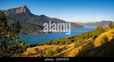 Le village de Savines-le-Lac avec son pont et le pic de Grand-Morgon en été le long du lac serre-Poncon. Hautes-Alpes, Alpes, France Banque D'Images