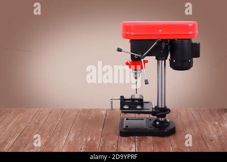 L'outil de travail des métaux - vue latérale Nouvelle perceuse presse rouge sur une table en bois et un fond marron. Banque D'Images