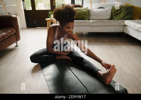 Belle femme stretching hamstrings pendant la pratique de yoga exercice dans moderne salon Banque D'Images