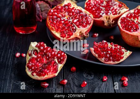 Grande grenade, en morceaux. Sur fond sombre. Les céréales sont dispersées à proximité. Concept d'automne. Vitamines, mode de vie sain. Copier l'espace. Banque D'Images