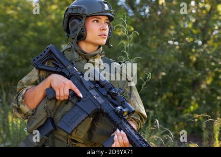 jeune femme militaire caucasienne tient une arme dans sa main dans la nature, elle va chasser, la chasse en forêt est un passe-temps. jeu avec des armes Banque D'Images