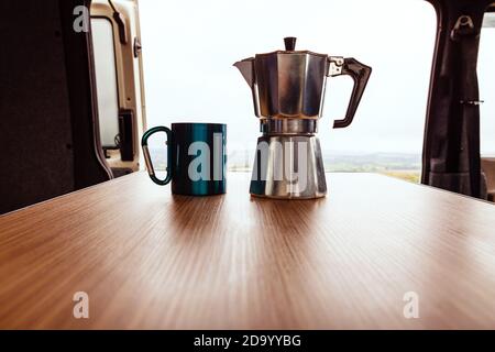 Machine à café Aqua bialetti et tasse de camping sur bois Table dans une fourgonnette T4 Banque D'Images