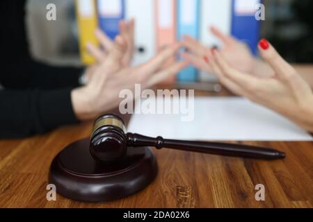 Le juge Gavel est allongé sur une table en bois dans le palais de justice à proximité. Les mains des hommes et des femmes gestuelle en arrière-plan Banque D'Images