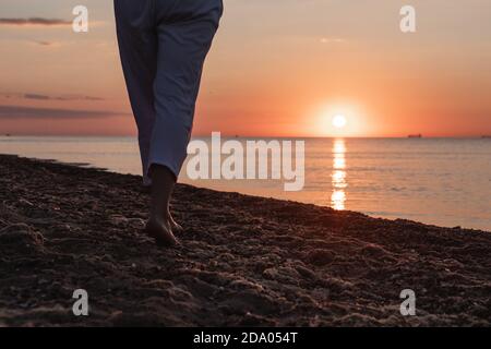 femme jambes à pied près de la plage de sable. coucher de soleil au-dessus de la mer Banque D'Images