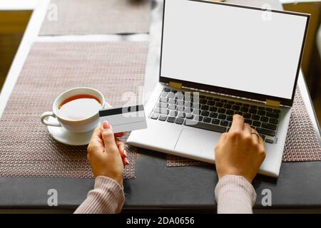 Vue rapprochée d'une femme qui fait le paiement par carte par l'application en ligne d'ordinateur portable dans un café. Concept de commerce électronique. Maquette. Banque D'Images