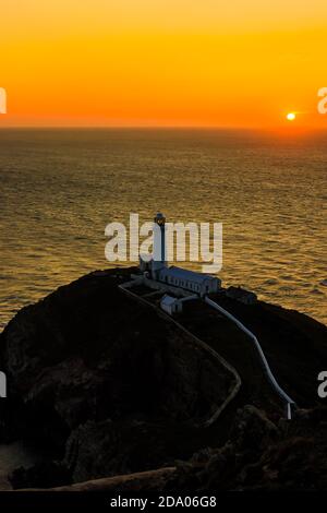 Un phare sur les falaises avec un coucher de soleil sur l'océan (South Stack Lighthouse, pays de Galles, Royaume-Uni) Banque D'Images
