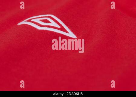 Logo Umbro brodé blanc argenté sur un maillot de sport rouge Banque D'Images