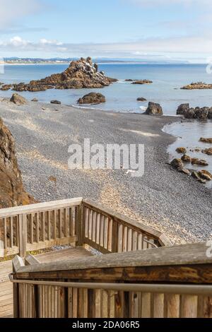 Vue panoramique sur Cobble Beach, sous le phare de Yaquina Head, avec des escaliers en bois au premier plan à Newport, Oregon Banque D'Images