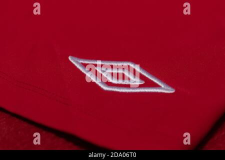 Logo Umbro argenté et blanc brodé sur un maillot de football rouge Banque D'Images