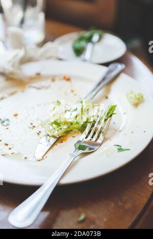 Vider l'assiette sale laissée après le dîner à table dans le café ou restaurant Banque D'Images