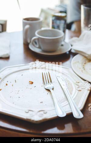 Vider l'assiette sale laissée après le dîner à table dans le café ou restaurant Banque D'Images