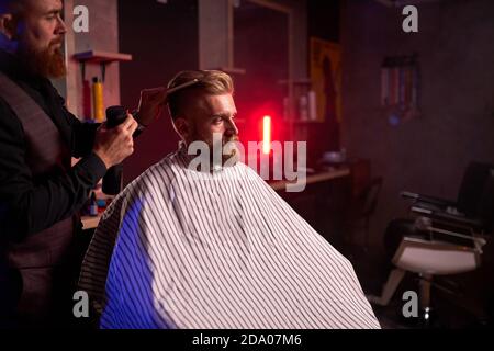 coupe de cheveux au salon de coiffure, en salon de coiffure masculin coupe les cheveux sur la tête du jeune client beau, le processus de création de coiffures pour les hommes par professionnel Banque D'Images