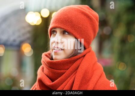 Portrait d'une fille dans un chapeau rouge et un foulard, une promenade dans la ville de Noël, un sourire sur son visage, temps frais, un regard fascinant Banque D'Images