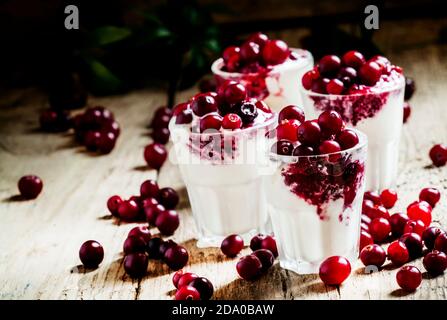 Dessert sucré de glace à la vanille avec sauce aux canneberges et baies canneberges fraîches, servi dans de petits verres sur le fond de bois ancien, sélectif Banque D'Images