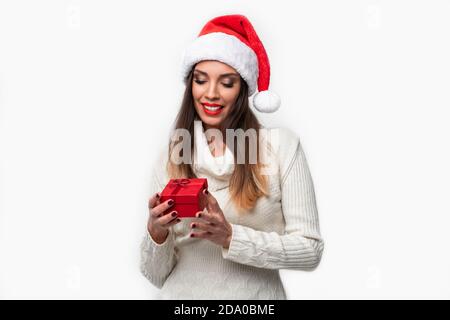 Beautifiul Close up portrait of young woman in red Santa hat on white background studio. Nouveau concept de vacances de Noël année surpris fille mignonne dents Banque D'Images