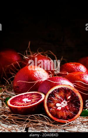 Oranges siciliennes rouges coupées en deux, arrière-plan en bois vintage, mise au point sélective Banque D'Images