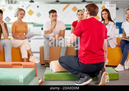 Cours de RCR avec de jeunes instructeurs caucasiens parlant et faisant la démonstration d'aide de premiers soins, mannequin de rcr sur le sol Banque D'Images