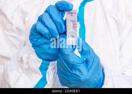 Un professionnel de la santé couvert d'une couverture blanche et de les gants bleus montrent un test rapide pour le contrôle de une contagion possible du covid-19 Banque D'Images