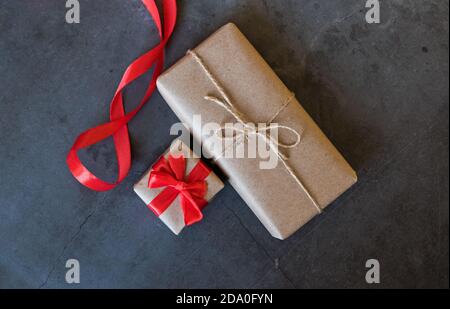 Boîtes-cadeaux emballées dans du papier Kraft avec un ruban rouge sur fond sombre Banque D'Images