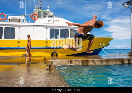 Les adolescents de sauter dans l'eau à côté du quai de Vaitape Bora Bora, îles de la société, Polynésie Française, Pacifique Sud. Banque D'Images