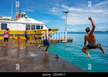 Les adolescents de sauter dans l'eau à côté du quai de Vaitape Bora Bora, îles de la société, Polynésie Française, Pacifique Sud. Banque D'Images