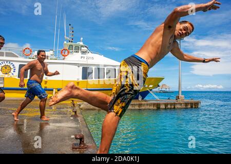 Les adolescents de sauter dans l'eau à côté du quai de Vaitape Bora Bora, îles de la société, Polynésie Française, Pacifique Sud. Banque D'Images