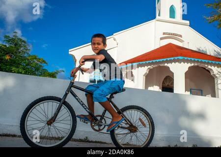 Garçon local en vélo dans l'église Rotoava à Fakarava, archipel de Tuamotus Polynésie française, îles Tuamotu, Pacifique Sud. Banque D'Images