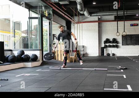 Mettre en place un haltérophile masculin dans une salle de gym moderne avec barbell et disques lourds pendant l'entraînement Banque D'Images