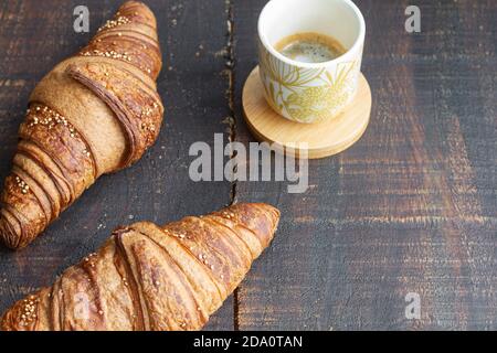Grand angle de croissants sucrés disposés sur une table en bois avec tasse de café aromatique pour le petit déjeuner à la maison Banque D'Images